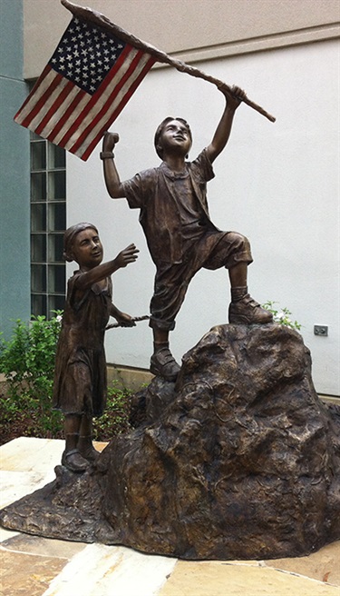 I Love My Country - This is a Patriotic Sculpture of a Boy and Girl Climbing to the Top of the Mountain. It is located on the south side of the Veterans Event Center. It was purchased by Randolph Rose.
